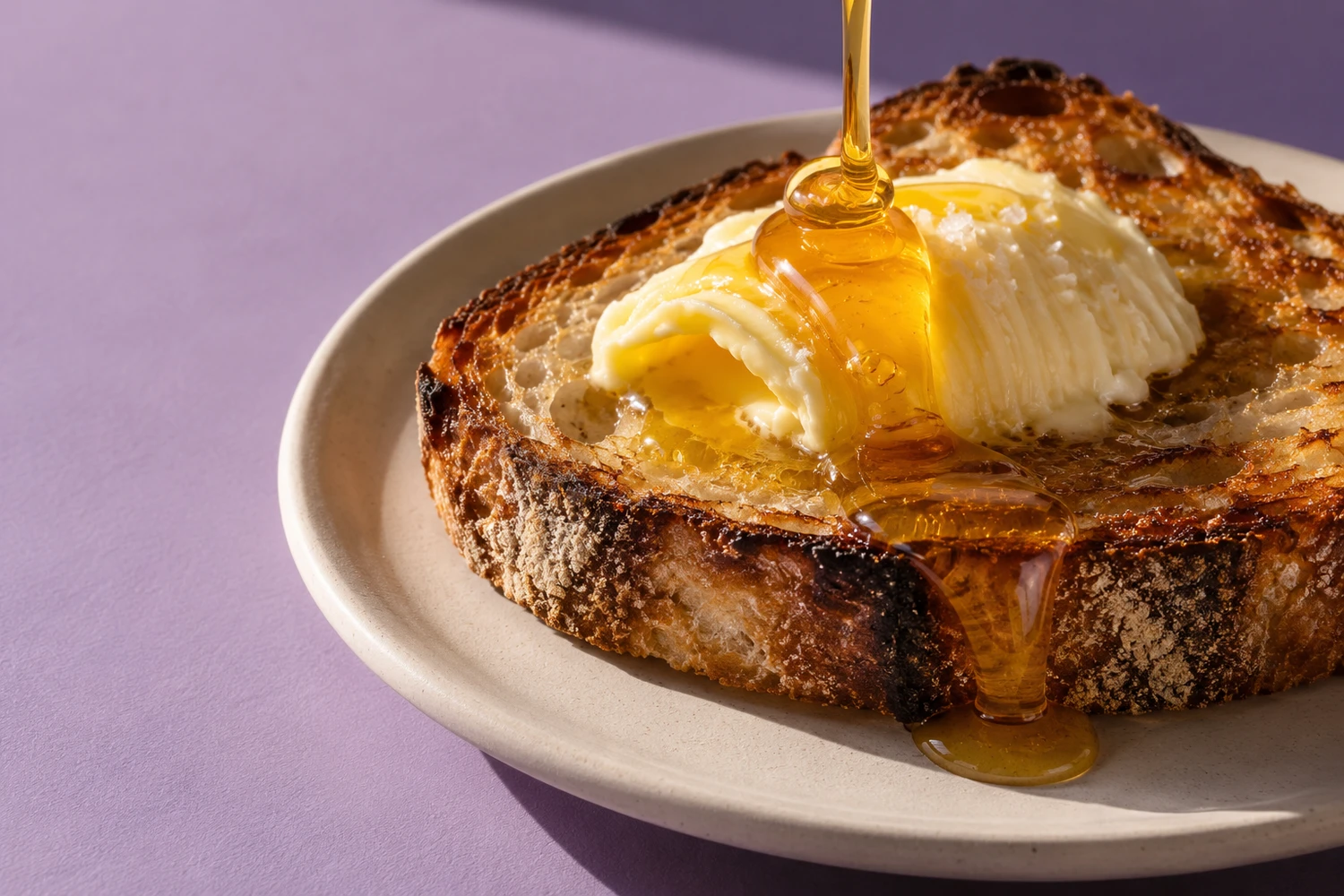 Thick golden honey drizzled over butter on warm sourdough toast